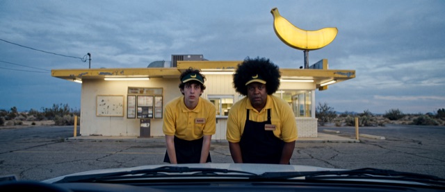 Two diner staff in yellow uniforms under a banana sign