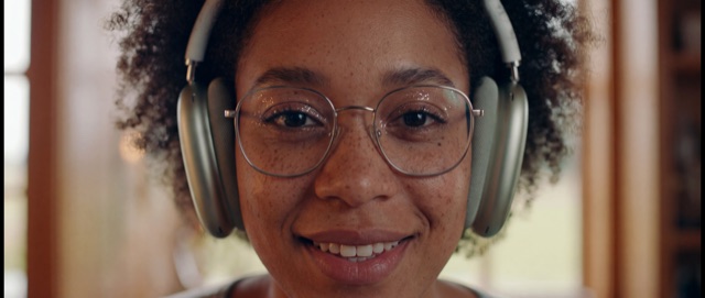 A smiling woman in glasses and headphones